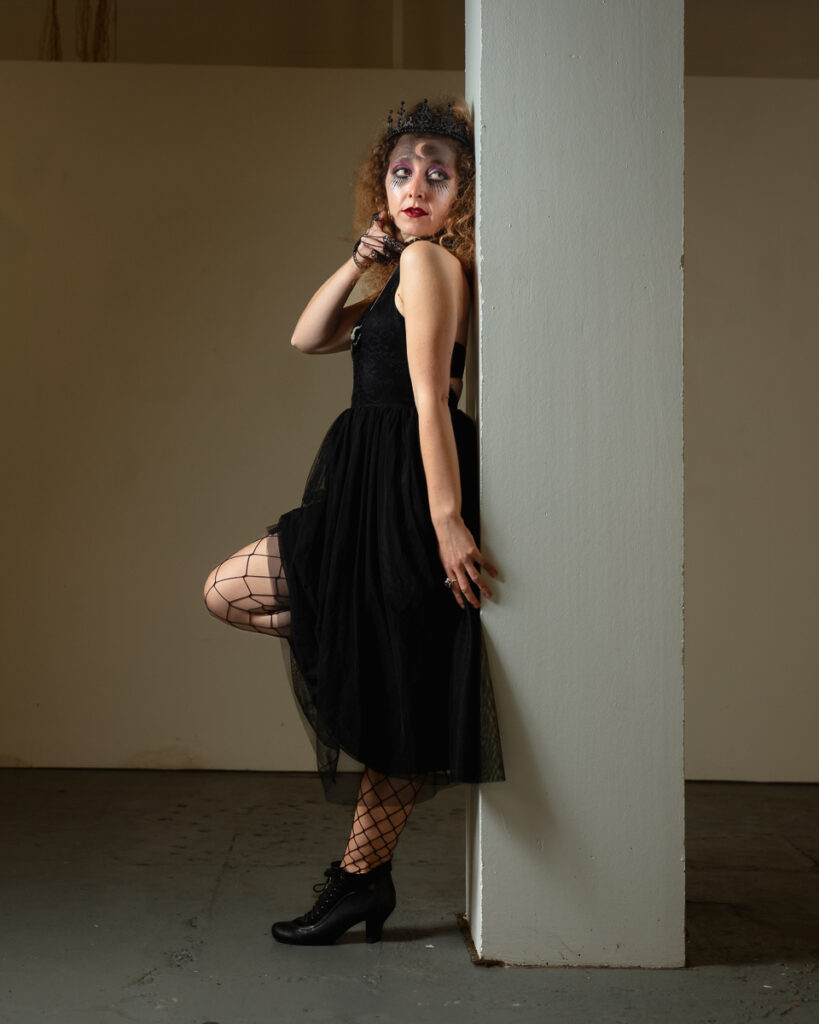 Woman in black dress posing against white column