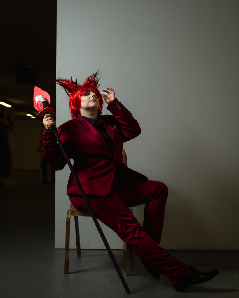 Person in red suit and wig holding megaphone seated
