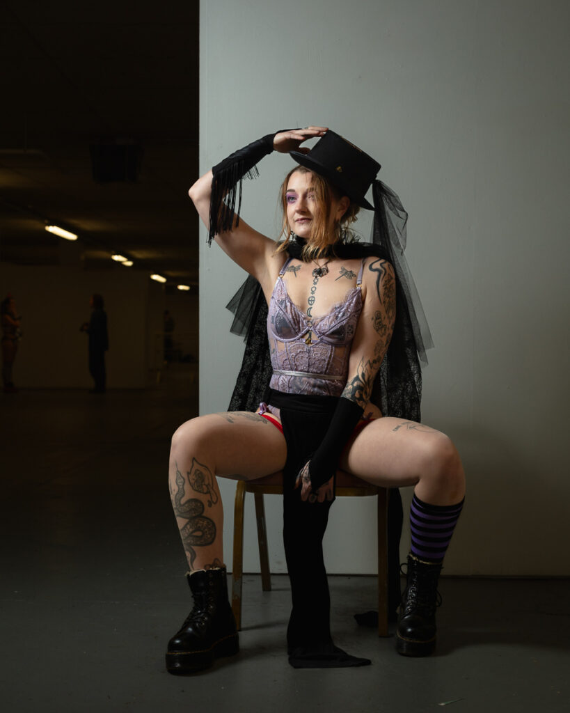 Tattooed woman in gothic outfit sitting on chair