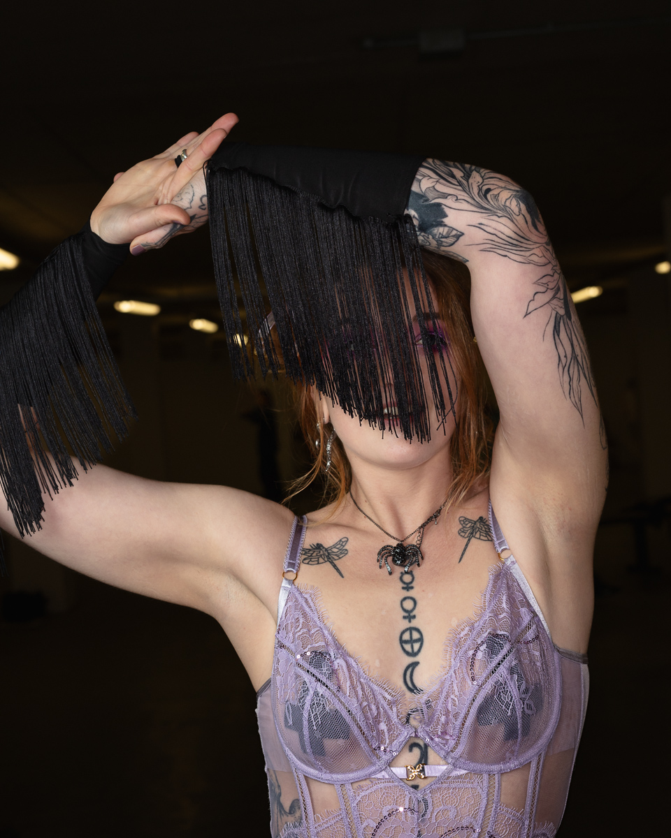 Woman with tattoos wearing black fringe and purple lingerie
