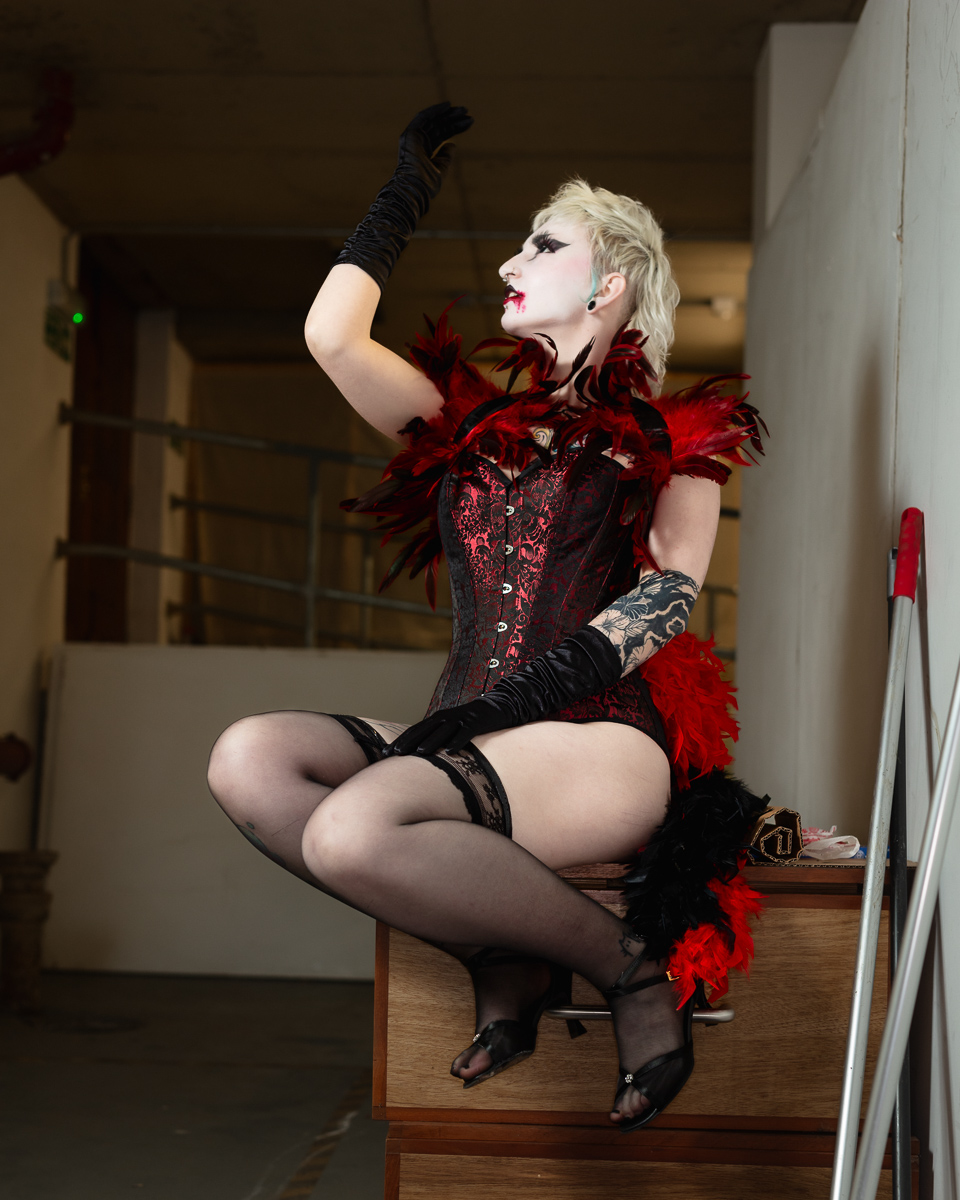 Performer in gothic corset and feather boa striking pose
