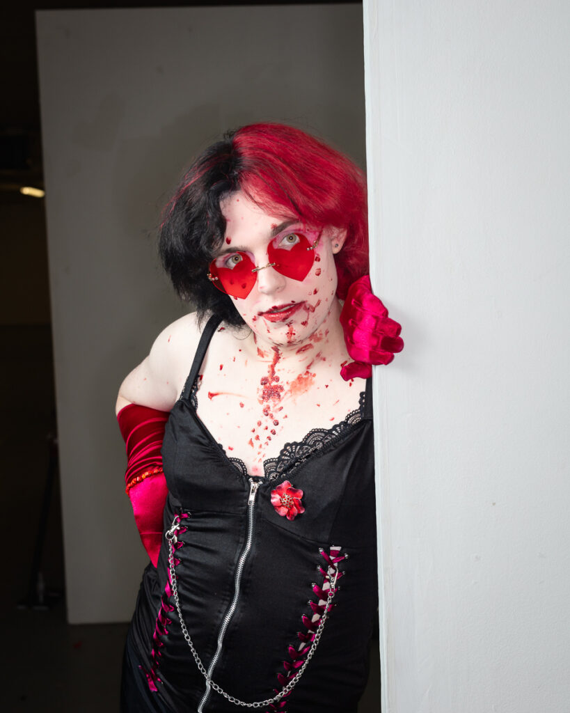 Person wearing red heart-shaped sunglasses with bold makeup