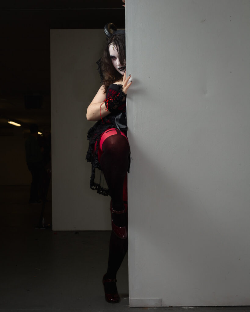 Gothic woman with horns peering around white wall