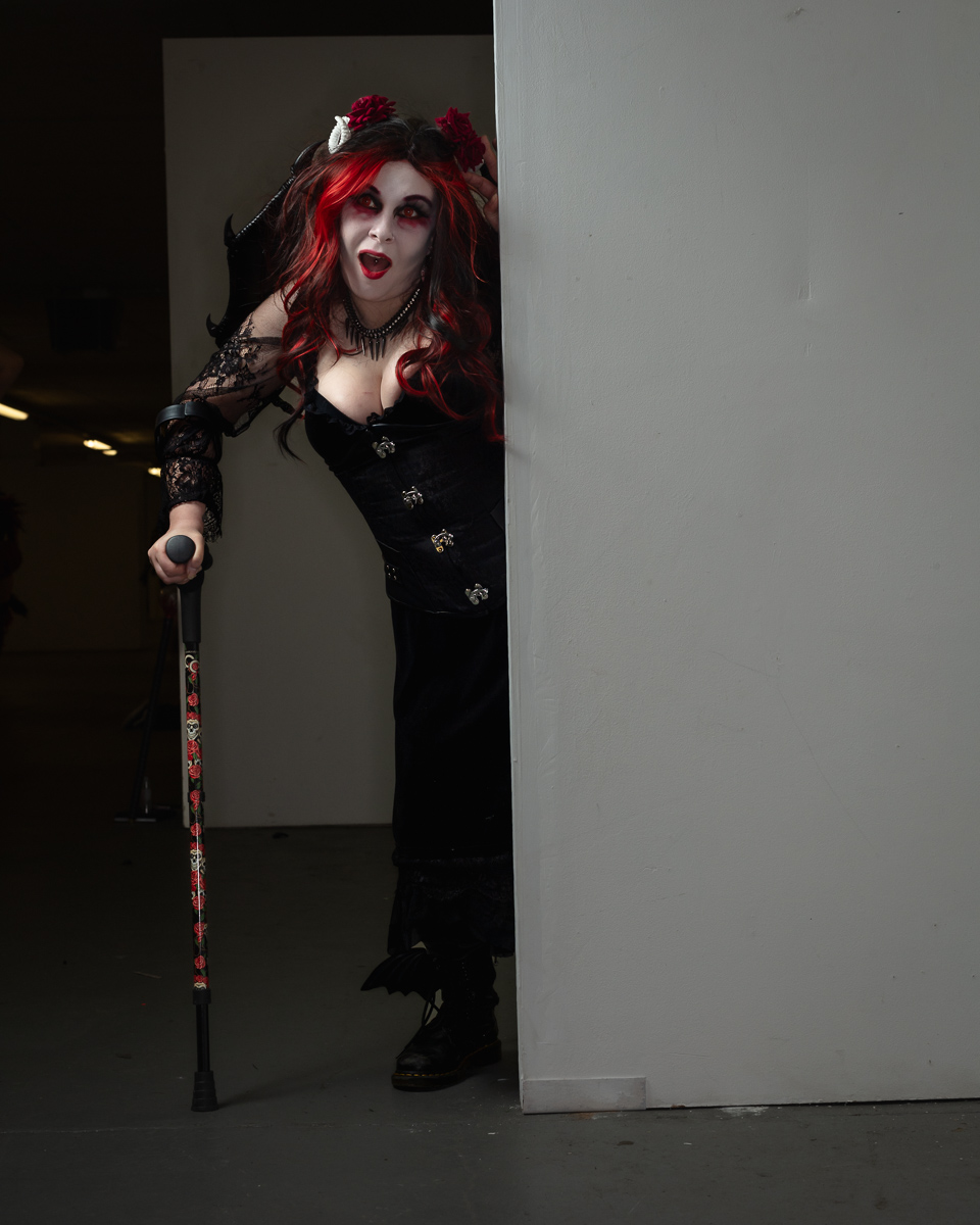 Goth character with crimson hair holding ornate cane
