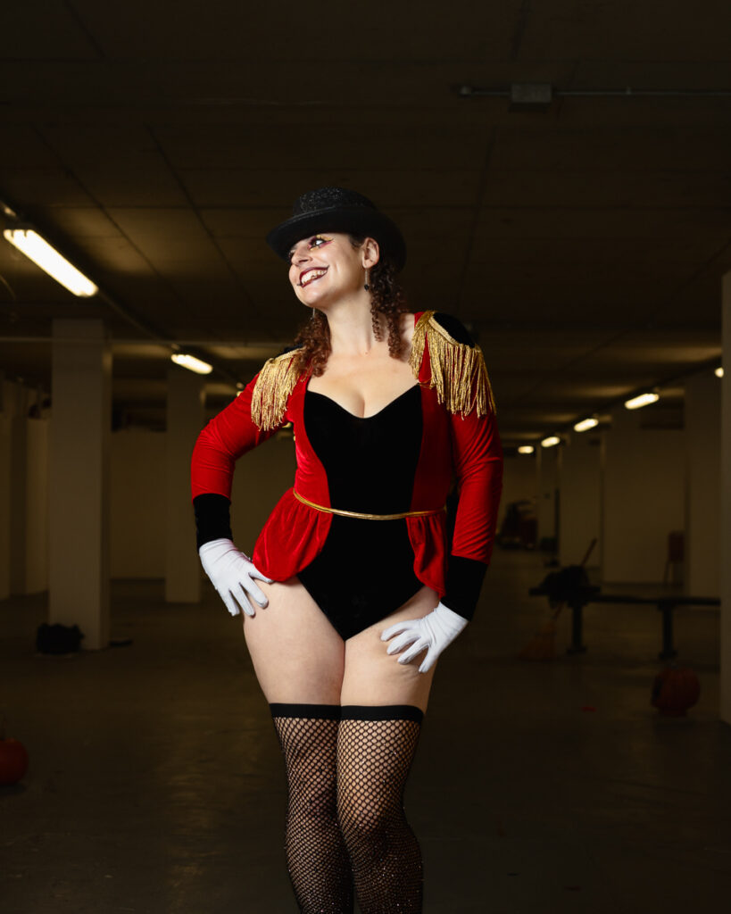 Woman in red ringmaster costume with top hat and fishnet stockings