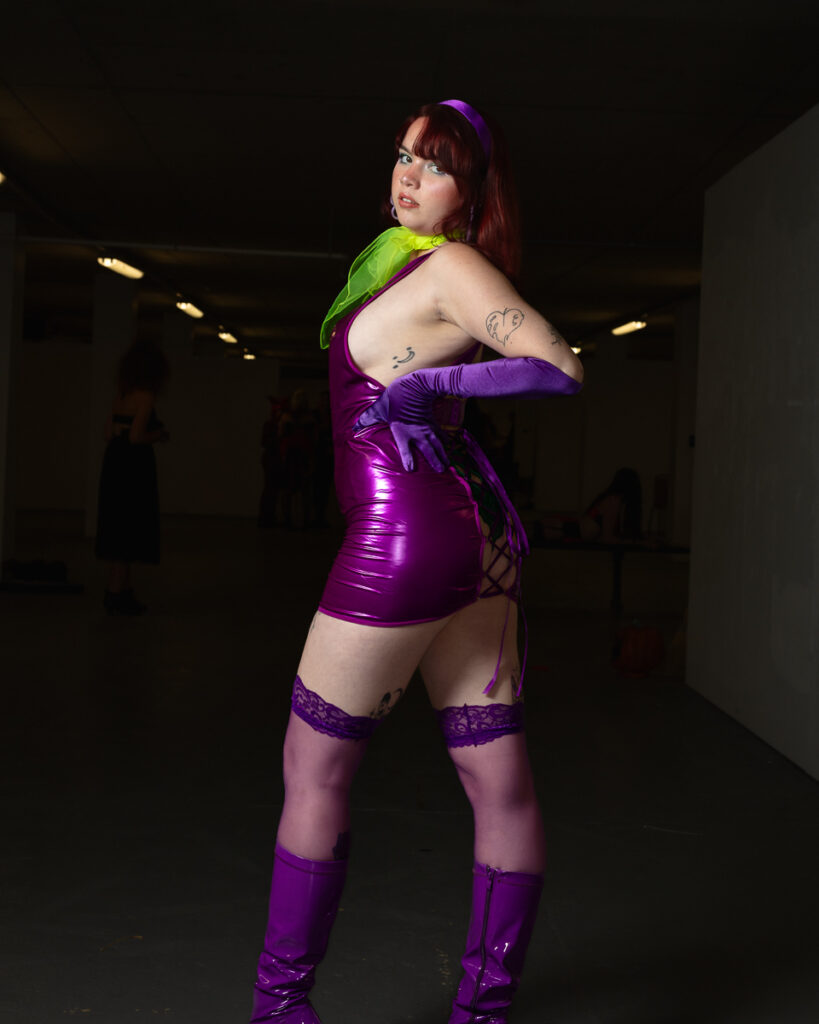 Woman in purple latex outfit with red hair posing