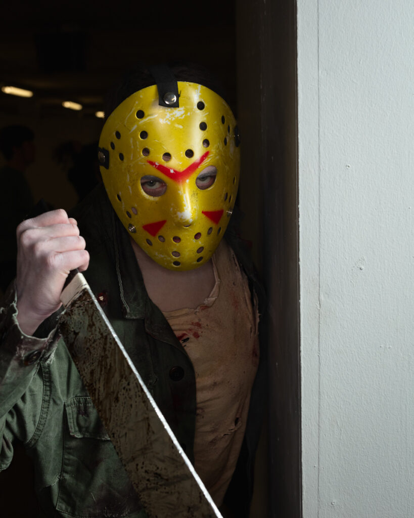 Person wearing yellow hockey mask holding knife menacingly