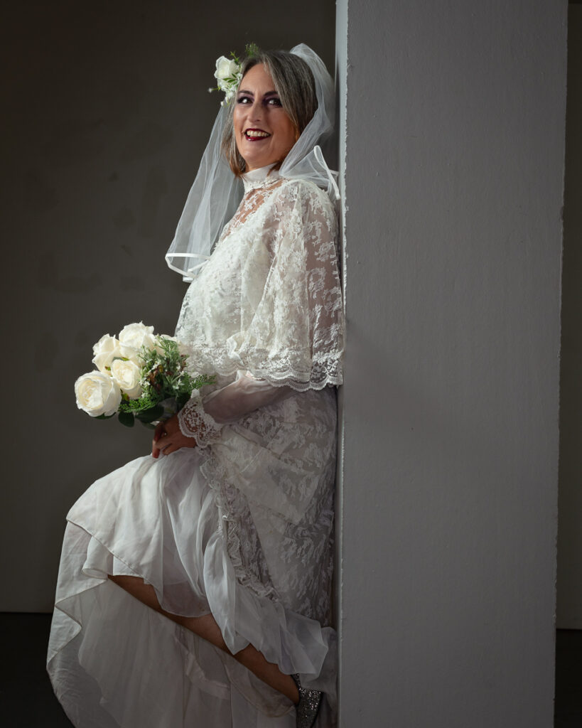 Bride in elegant lace wedding dress holding white rose bouquet