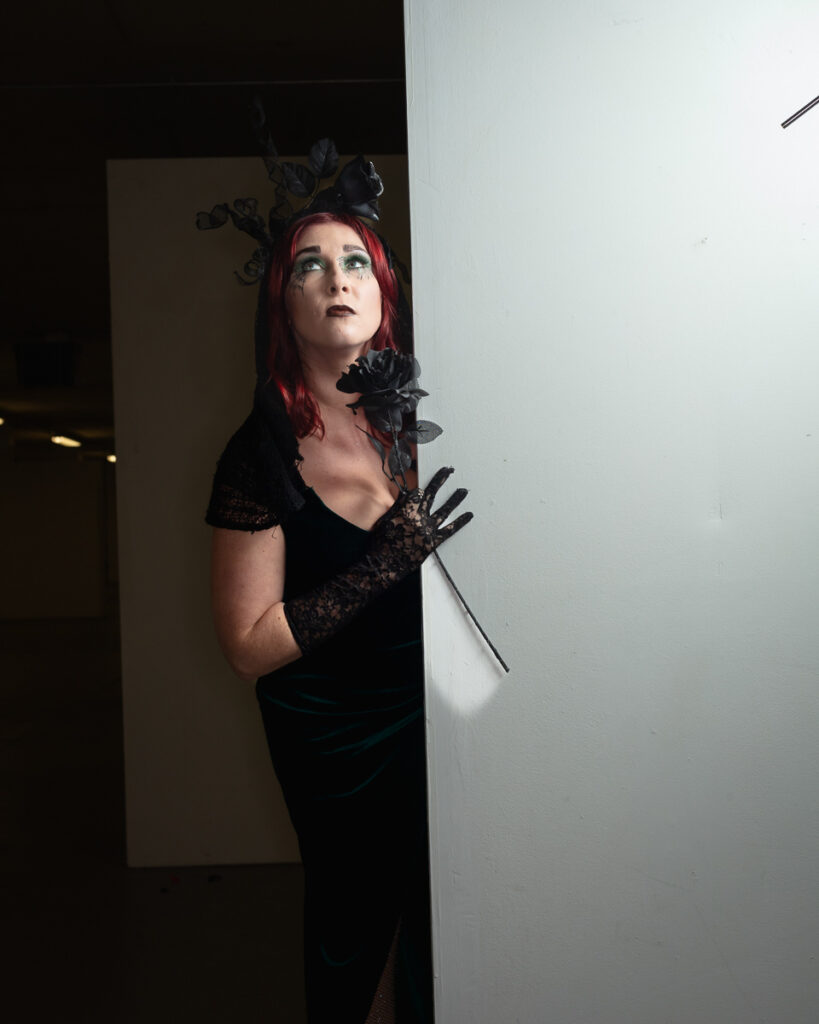 Woman with crimson hair in gothic black outfit with flowers