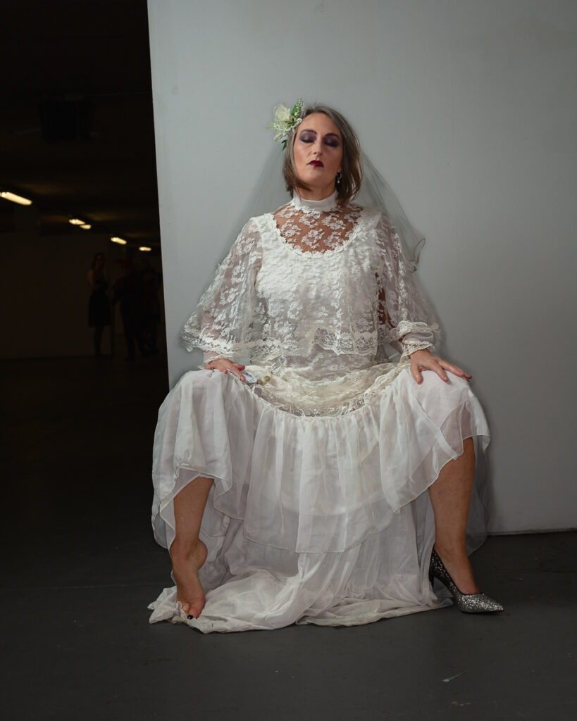 Bride in vintage lace wedding dress with floral crown seated