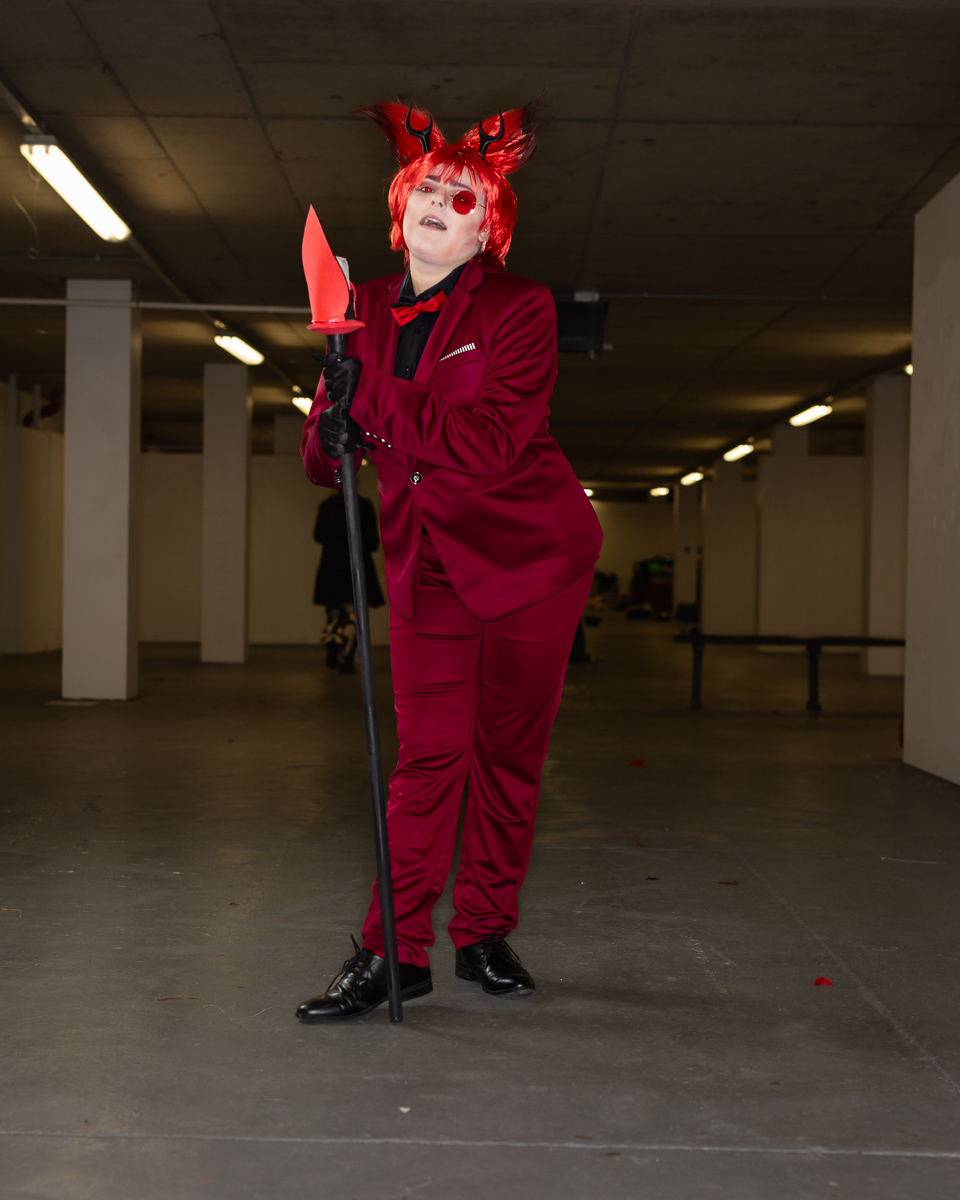 Person in red suit holding glowing sword cosplay costume