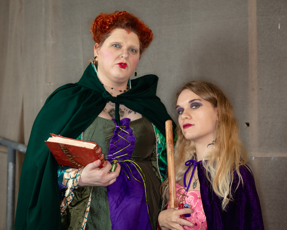 Two people in Halloween witch costumes with props.