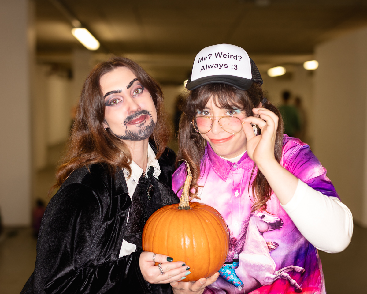 Two people in costumes holding a pumpkin.