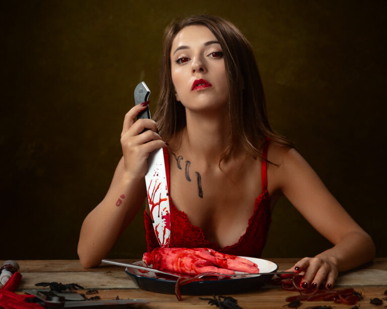 Woman in red dress holding knife with fake blood