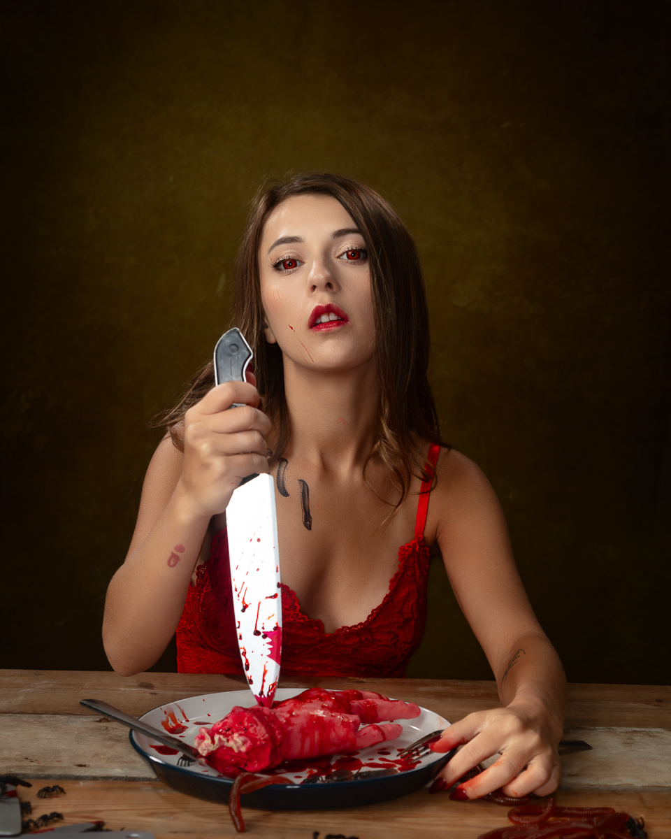 Woman with red eyes holding knife over bloody plate