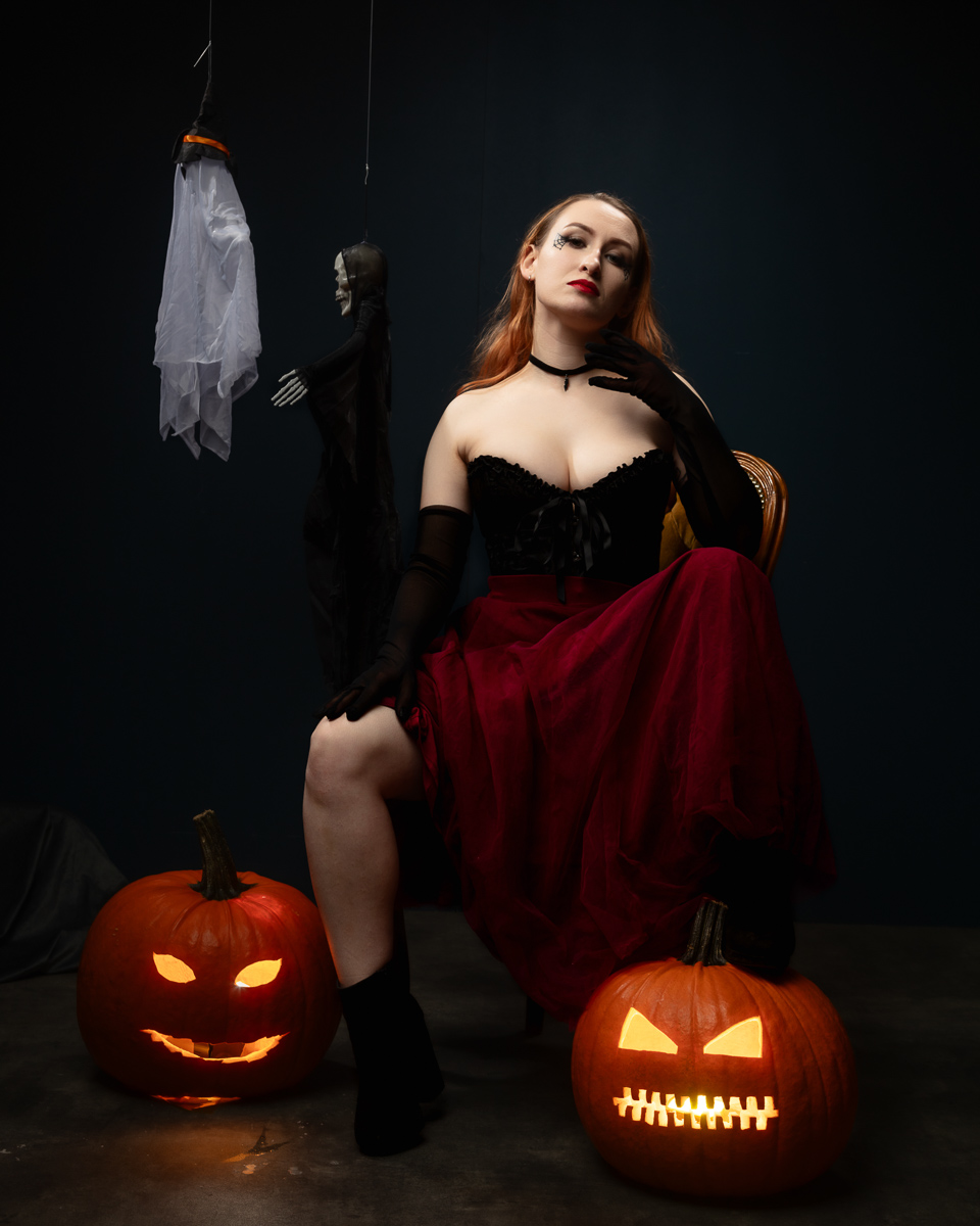 Woman in gothic Halloween costume with illuminated jack-o'-lanterns