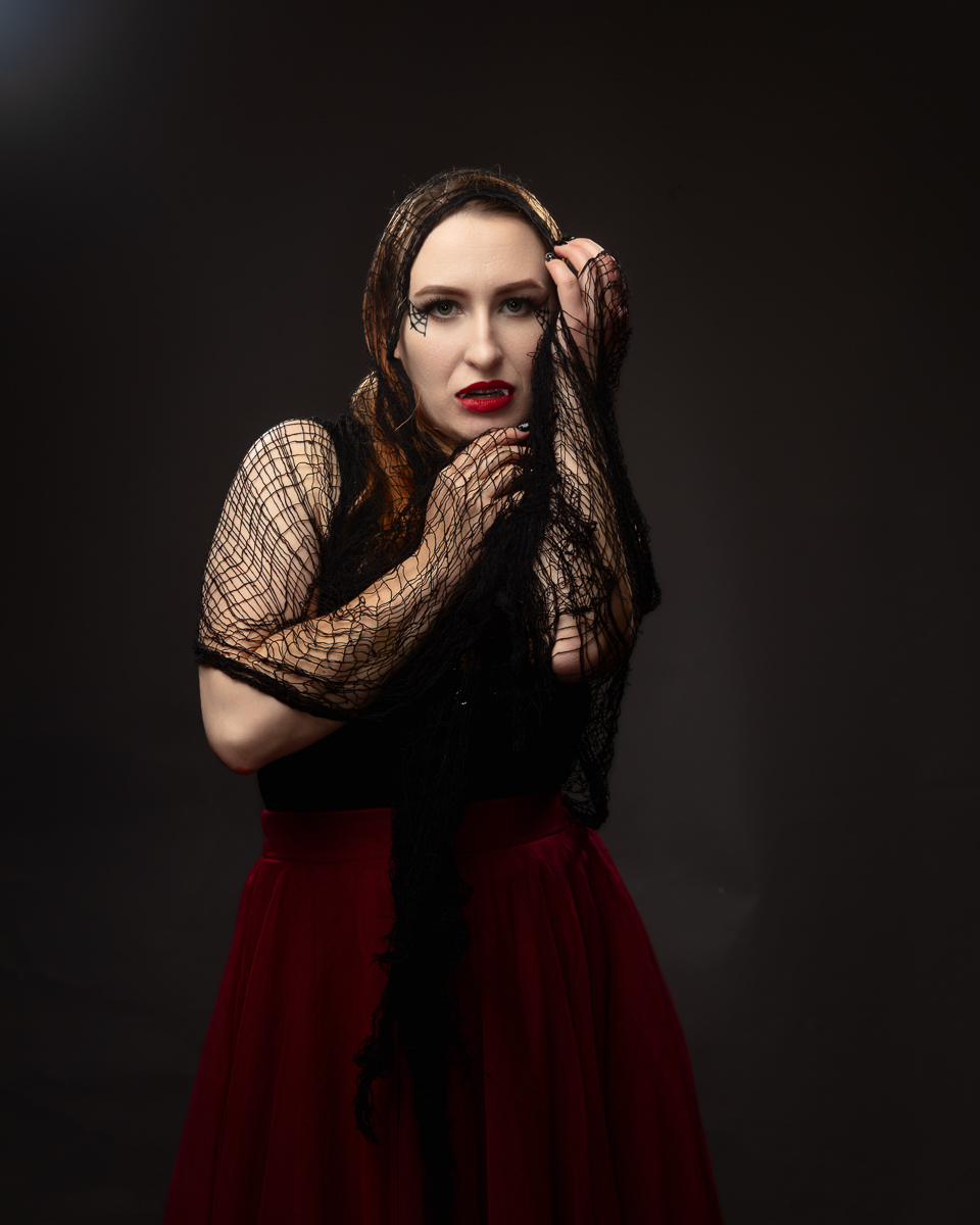 Woman in black lace and red skirt against dark background