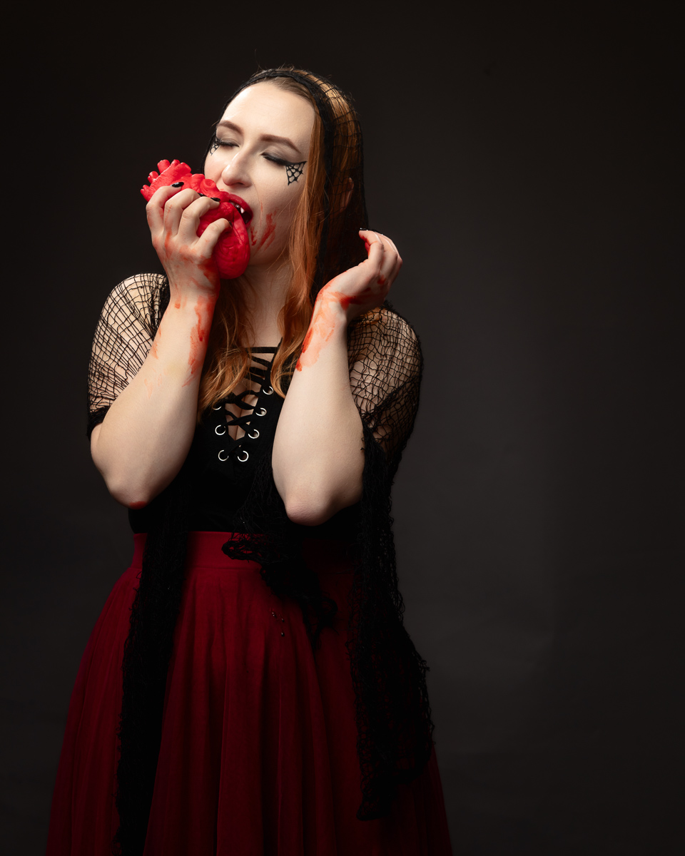 Woman with red flowers and theatrical makeup against dark background