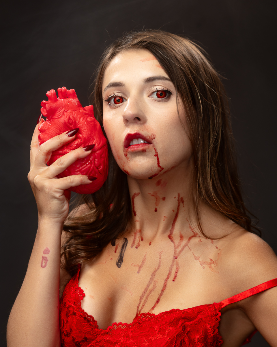 Woman with red eyes holding anatomical heart model