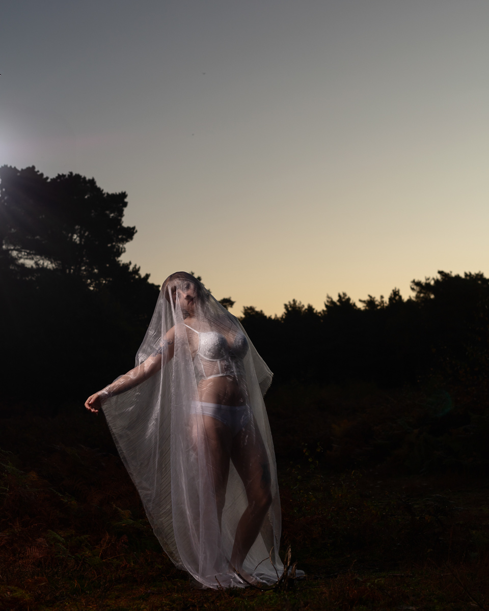 Woman wearing sheer veil at sunset with forested background