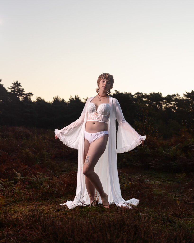 Woman in white lingerie and robe posing in rural field
