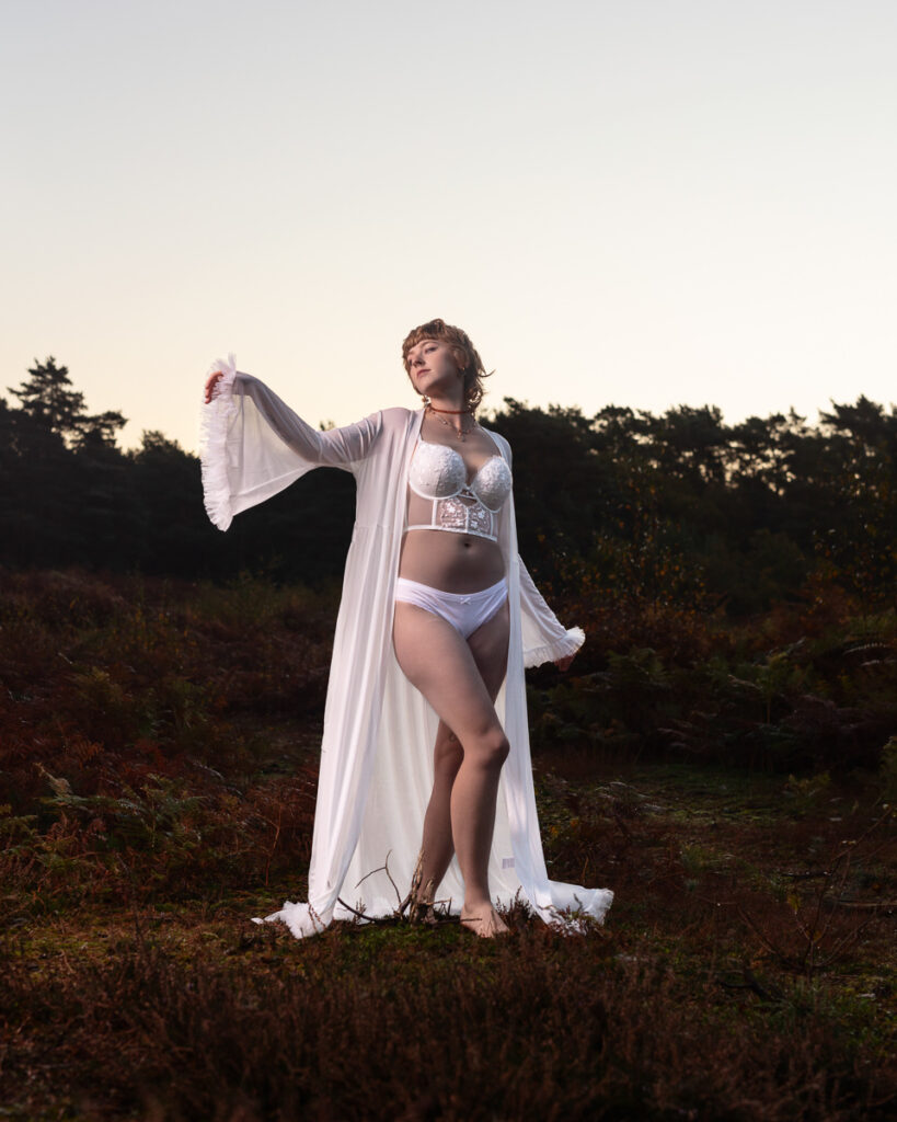 Woman in white lingerie and robe in rural landscape