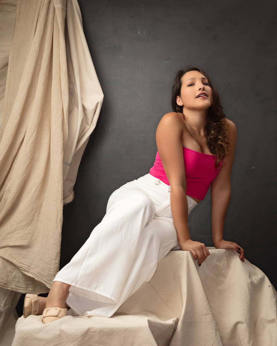 Woman in pink top and white trousers posing artistically