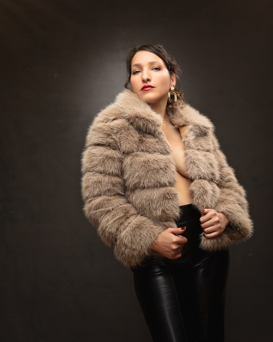 Woman wearing luxurious beige fur coat and gold earrings