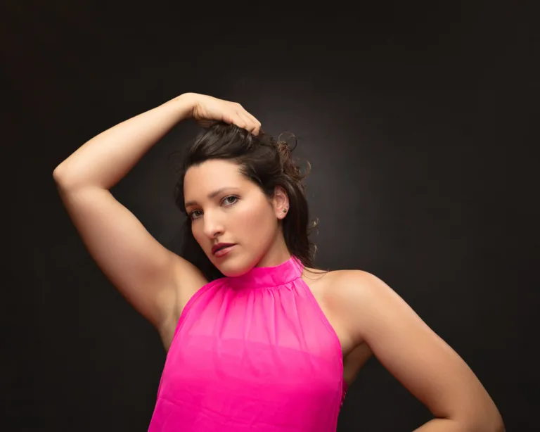 Woman in bright pink halter top against dark background