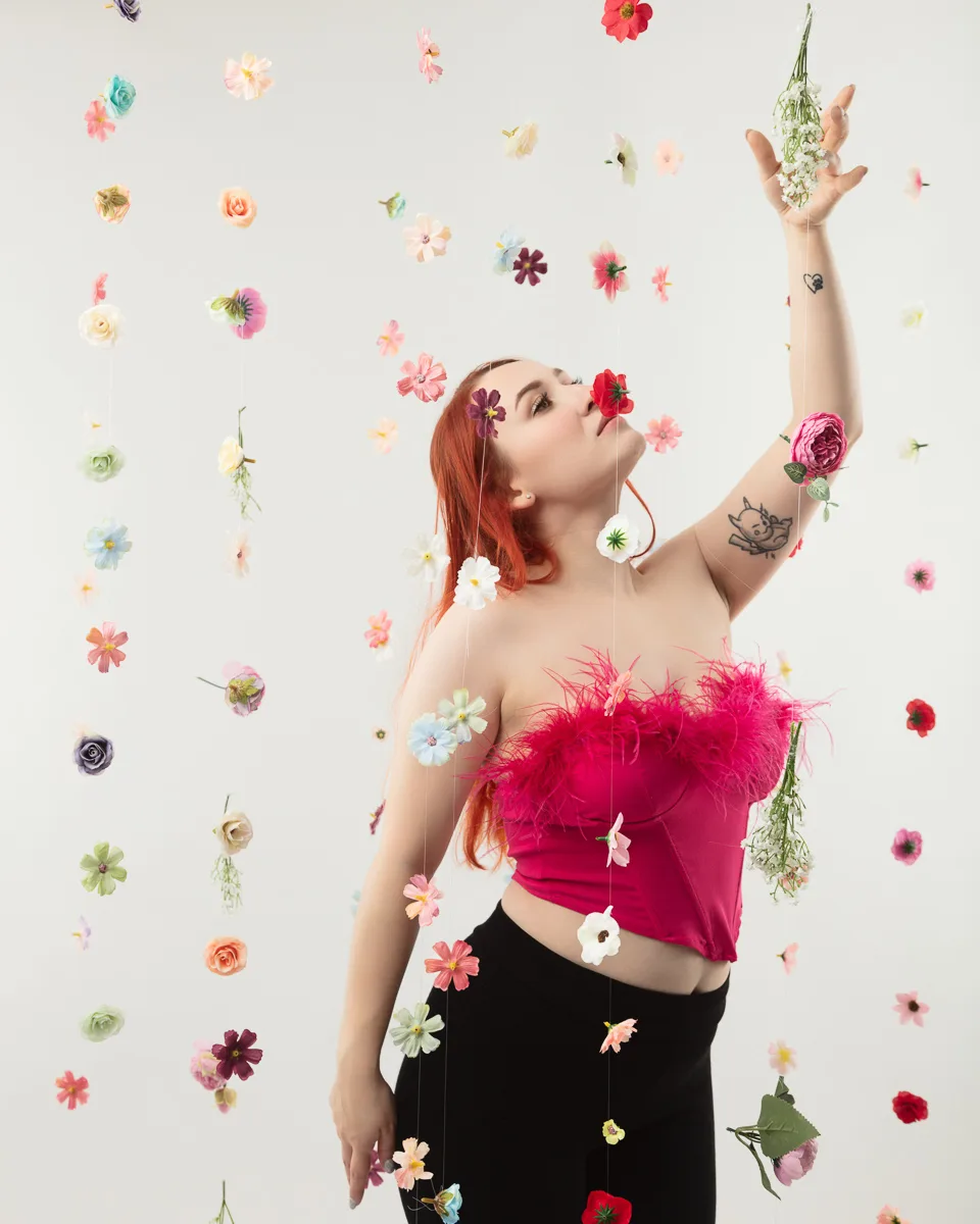 Woman with red hair surrounded by colorful floating flowers