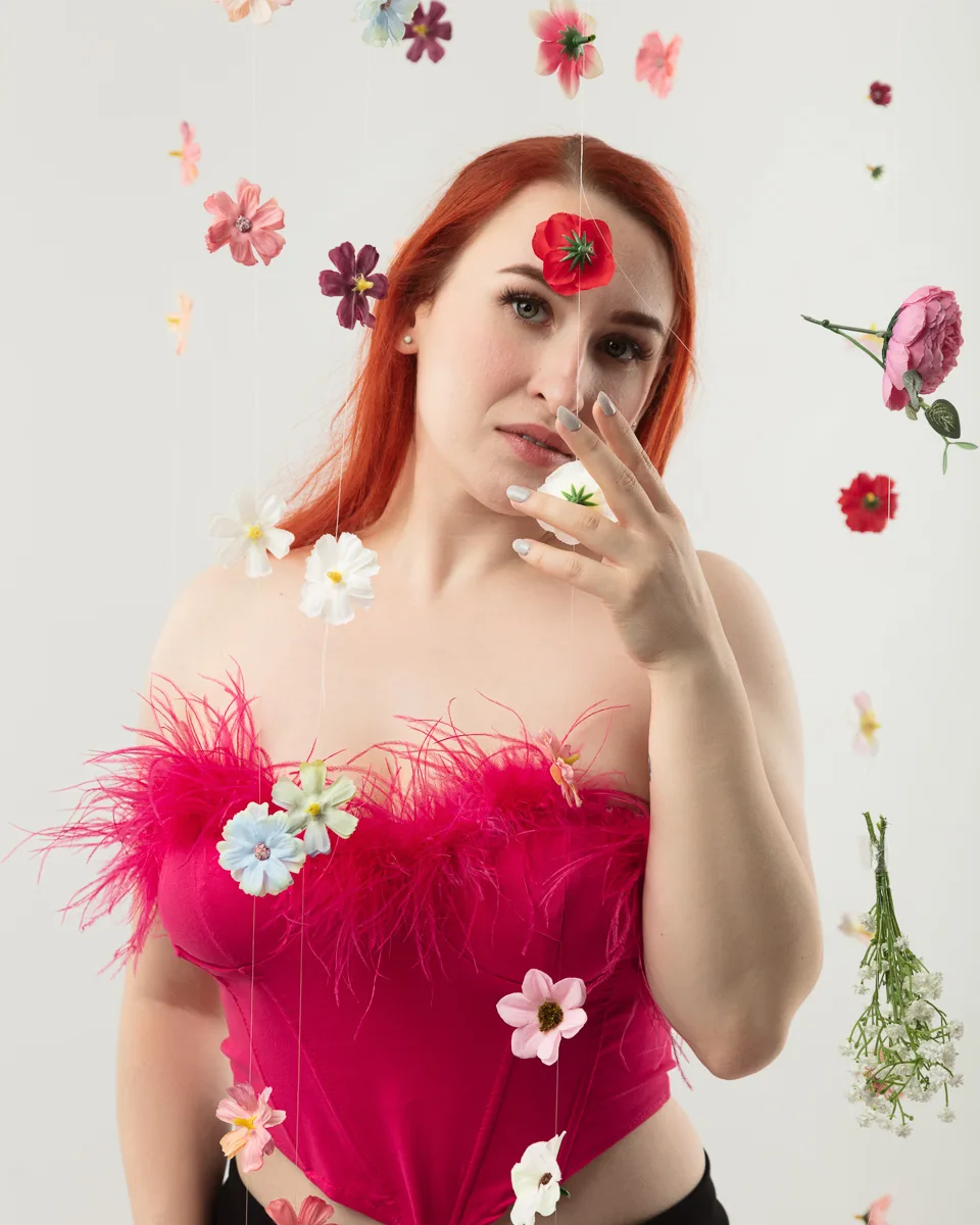 Red-haired woman surrounded by colourful floating flowers