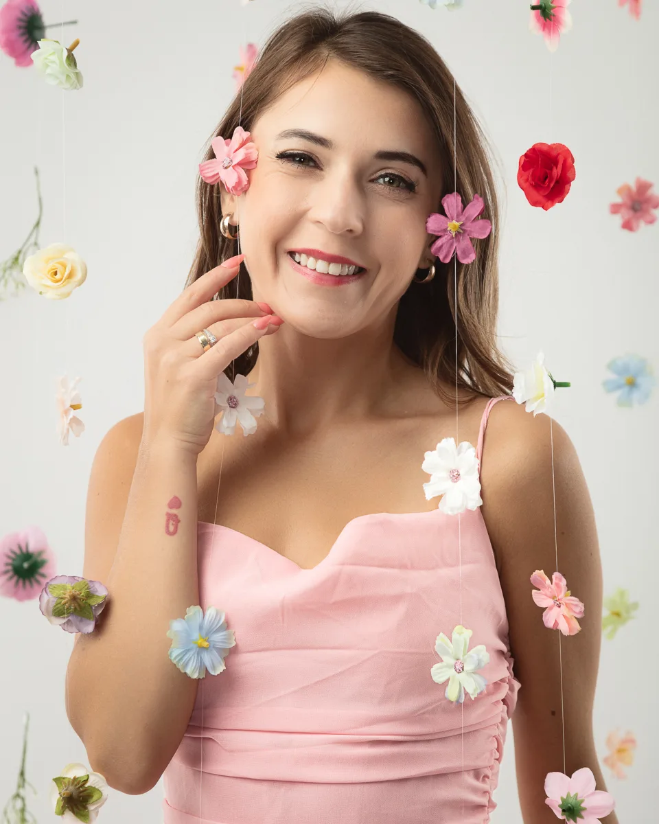 Smiling woman in pink dress surrounded by colourful flowers