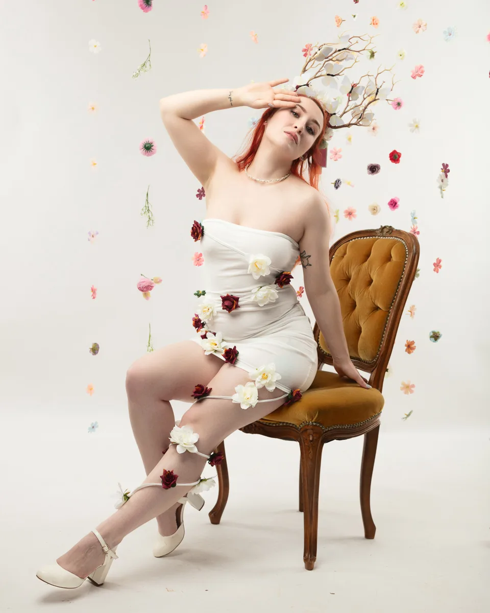 Woman with red hair sitting on vintage chair surrounded by flowers
