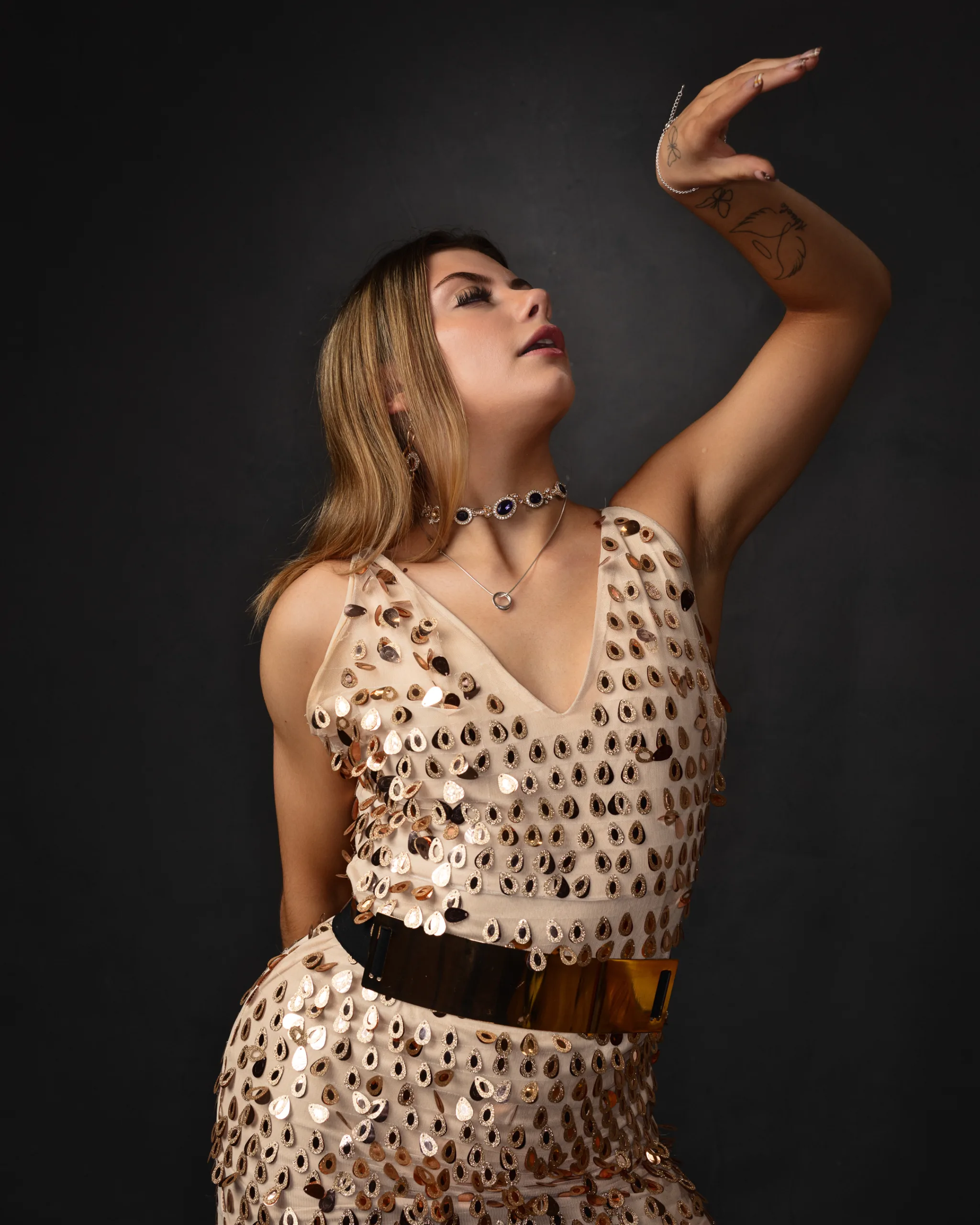 Woman in sequin dress posing elegantly.