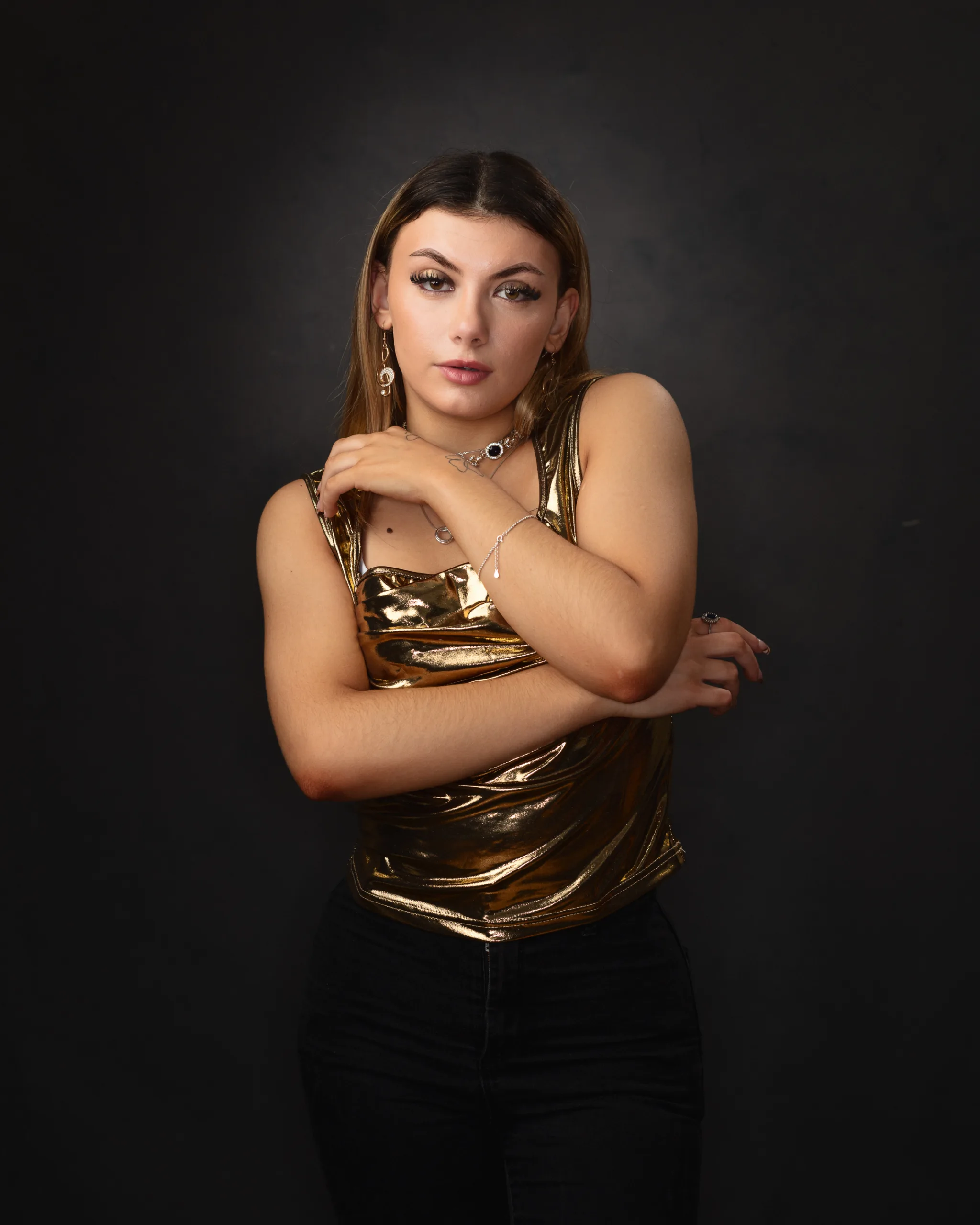 Person wearing gold top against dark background