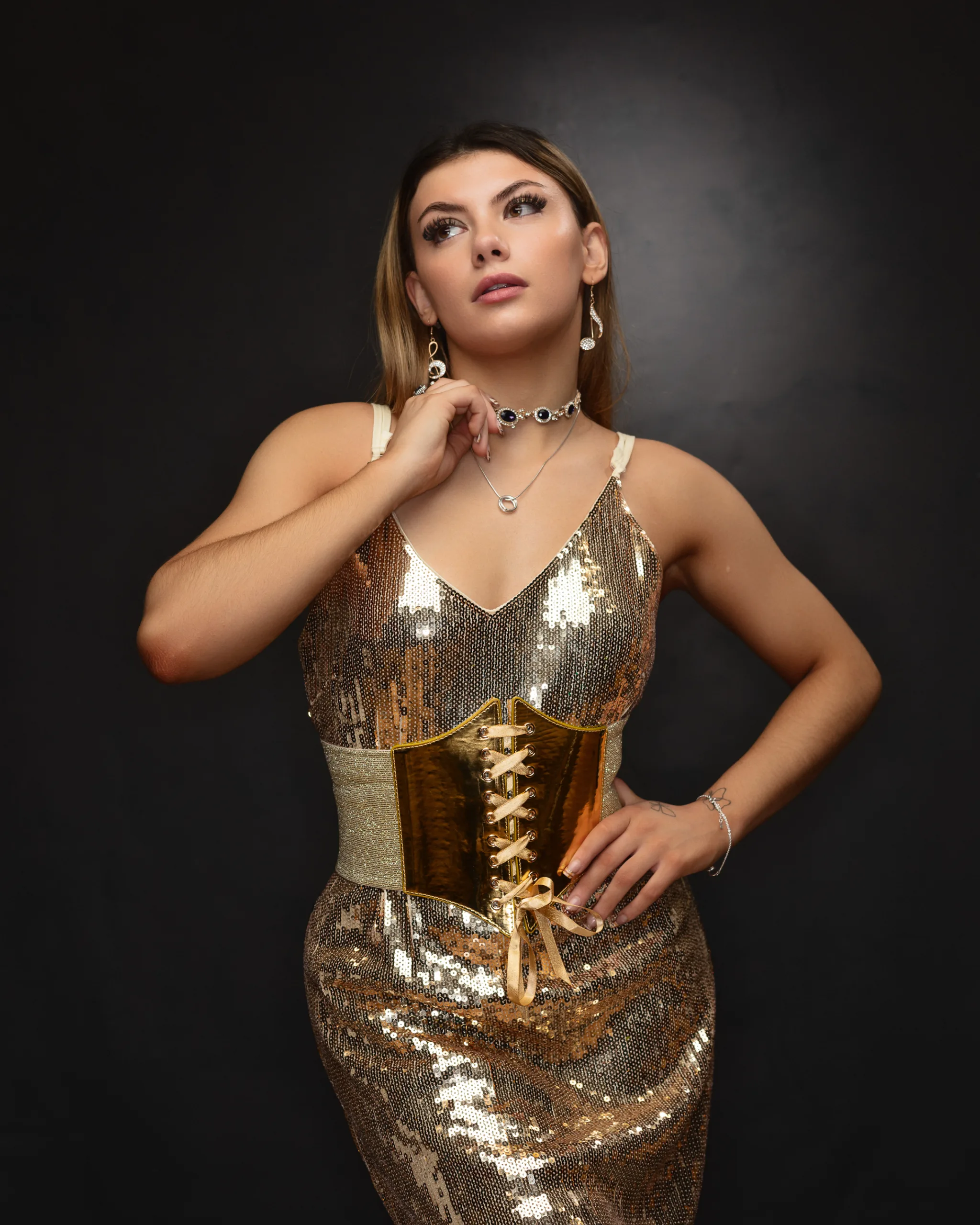 Woman in gold sequin dress against black background.