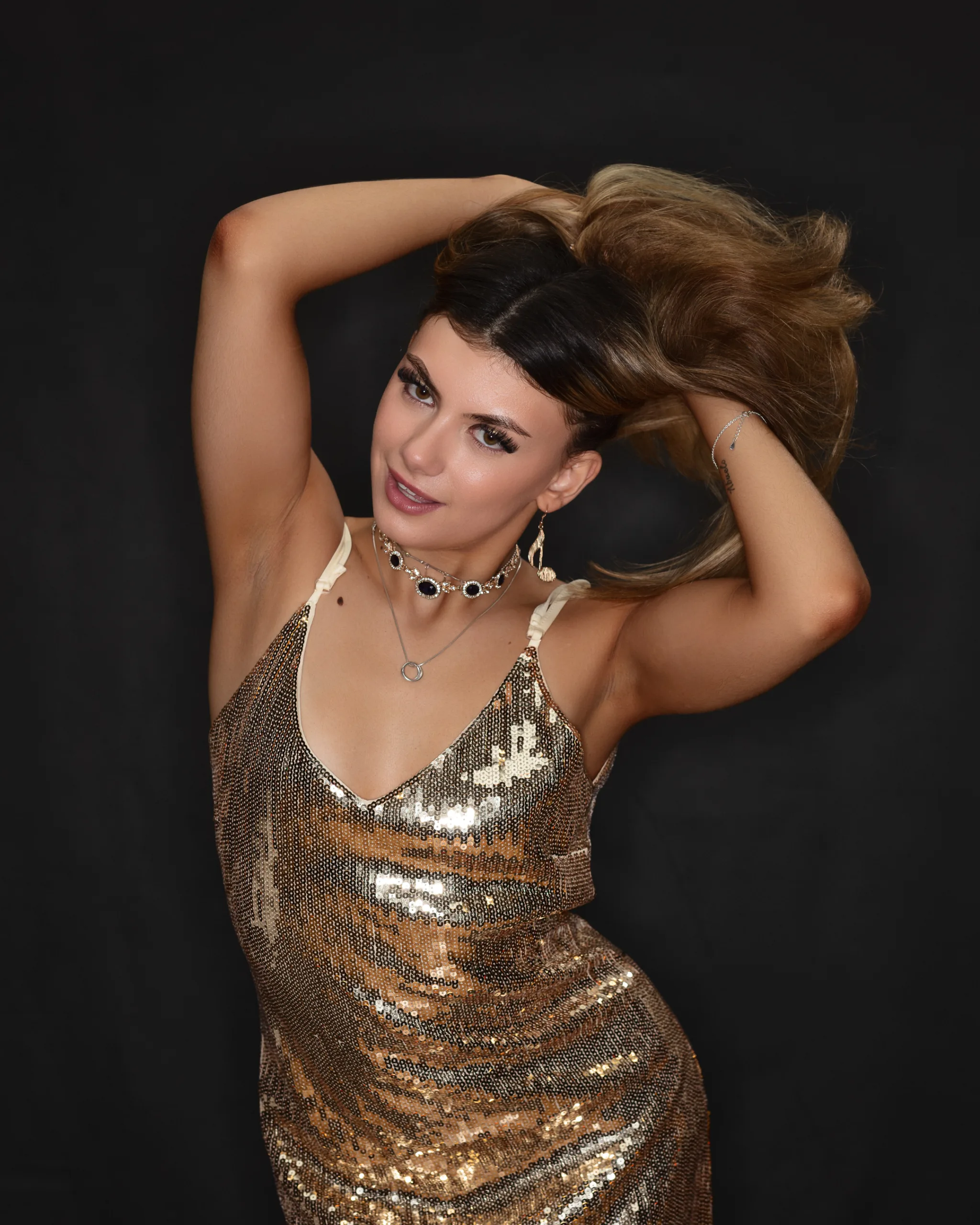 Woman in gold sequin dress posing stylishly.