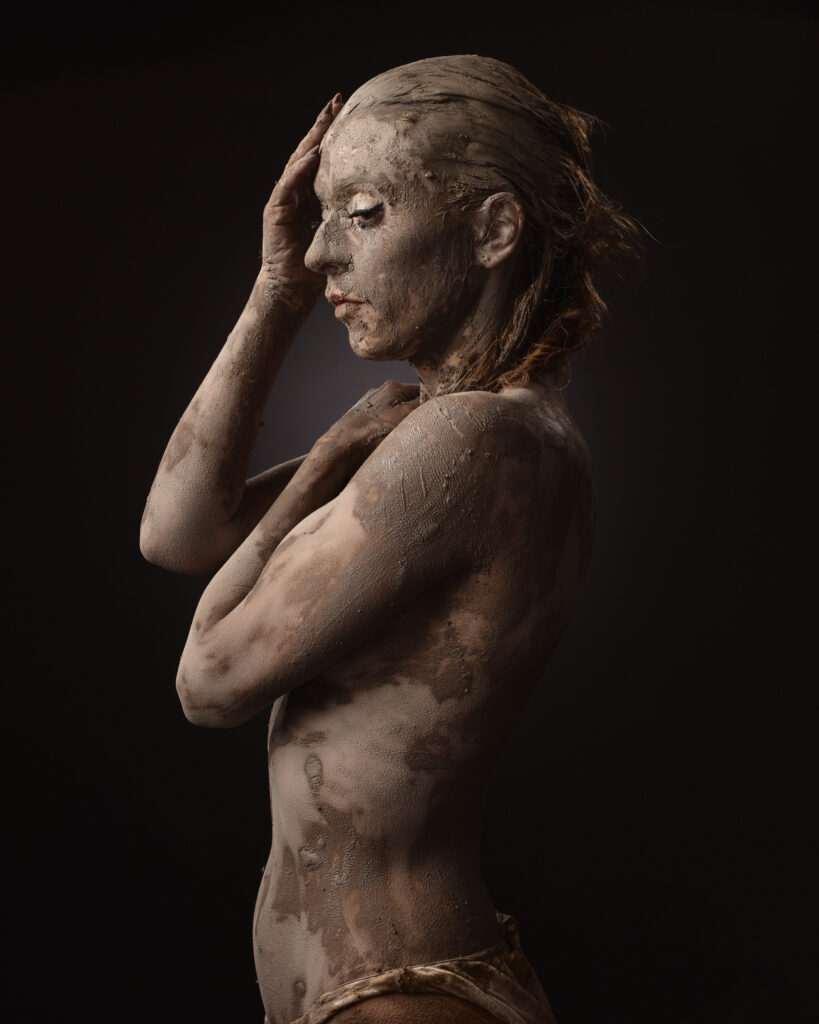 Mud-covered person in contemplative pose