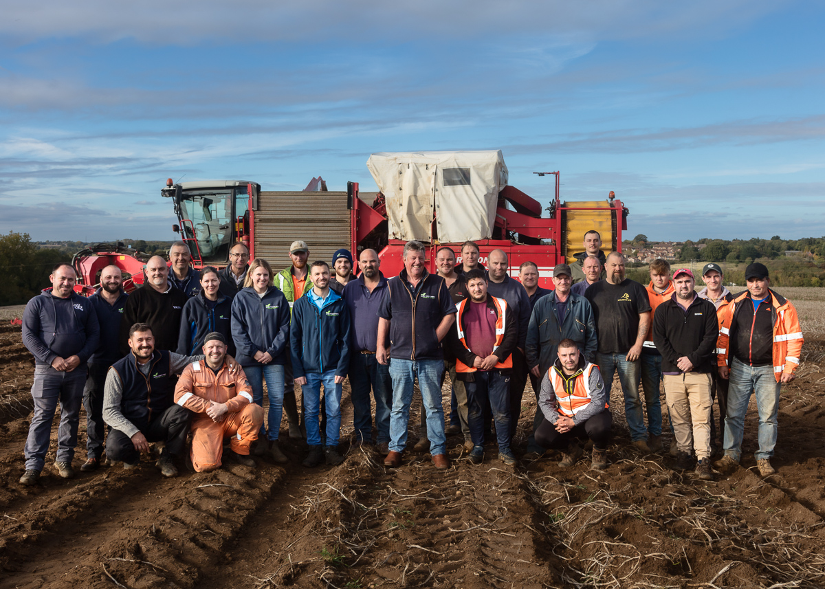 Team photograph of farm staff in front of a potato harvester for James Foskett Farms