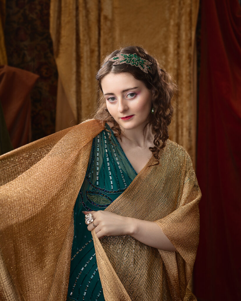 Woman in vintage dress with golden shawl, elegant setting.