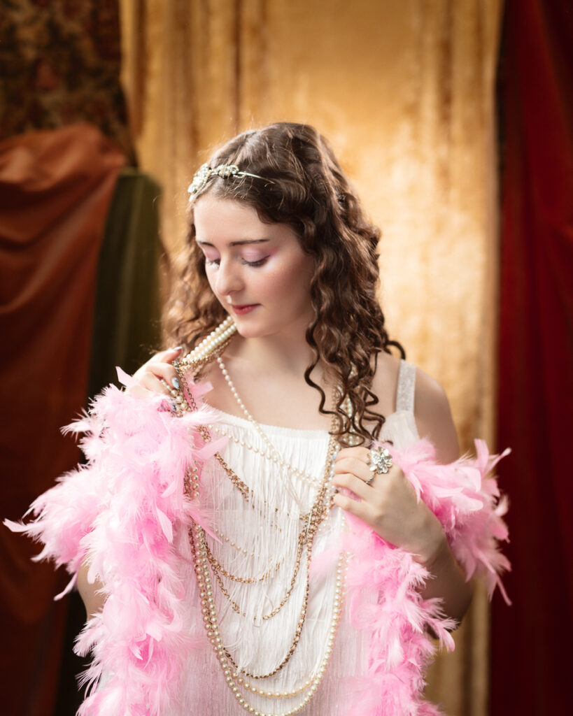 Woman in vintage dress with pearls and feathers.