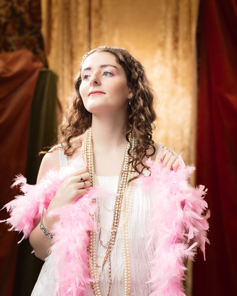 Woman in 1920s dress with pearls and boa.