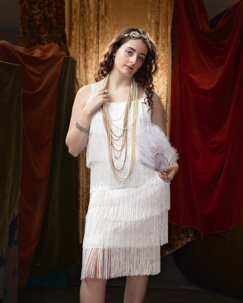 Woman in vintage Roaring Twenties attire with fan.