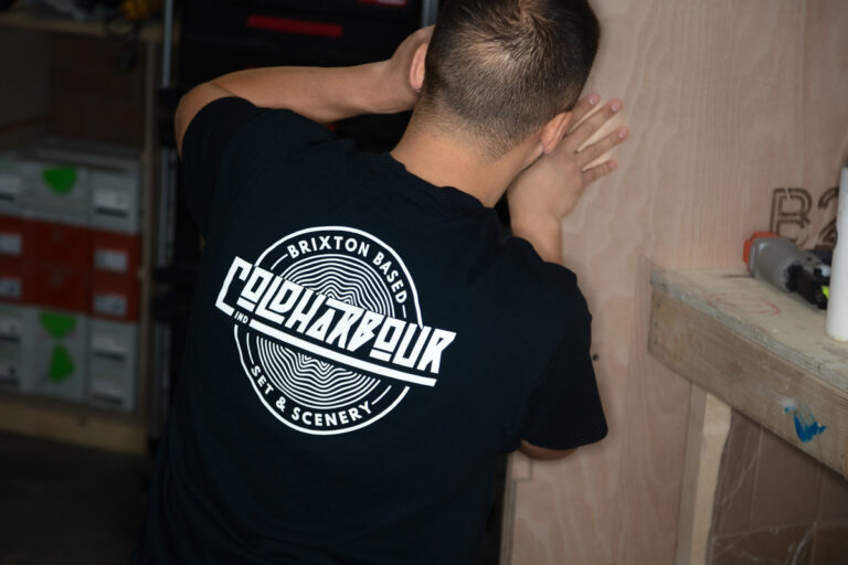 Person in Coldharbour shirt, facing away, adjusting plywood.