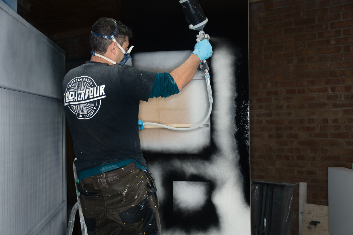Person spray painting black number on surface