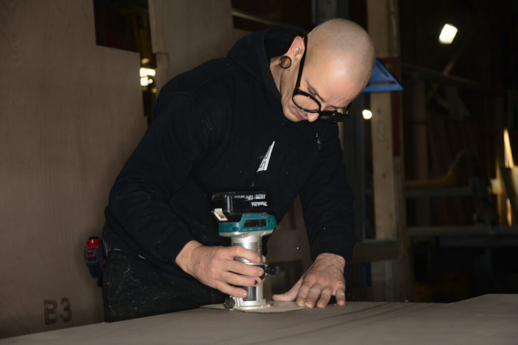 Person using a router tool on wood.