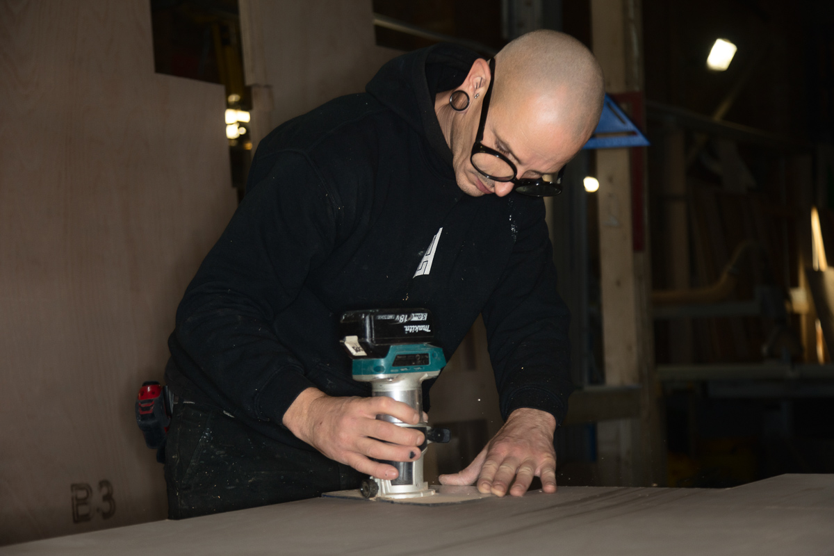 Person using a router tool on wood.