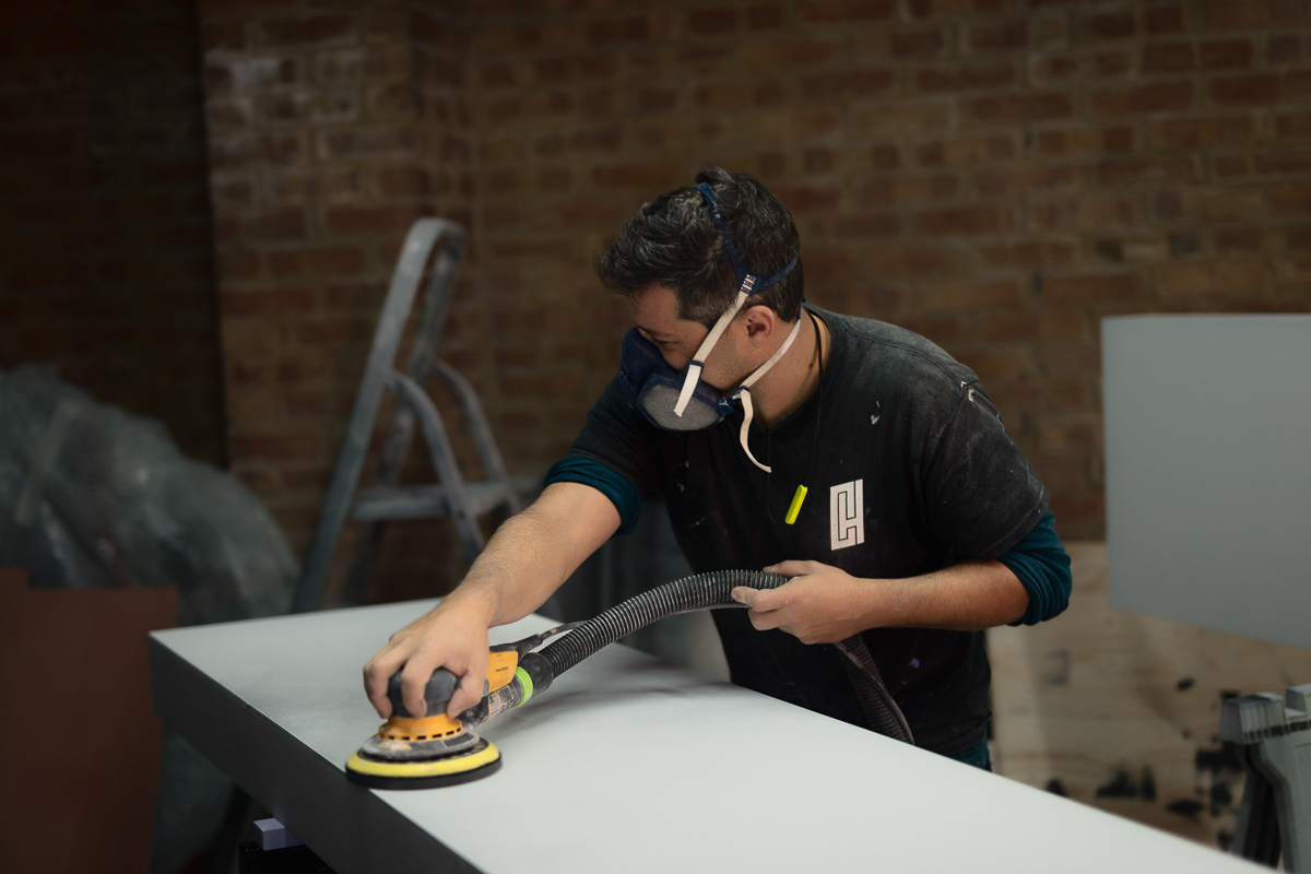 Man sanding worktop in workshop