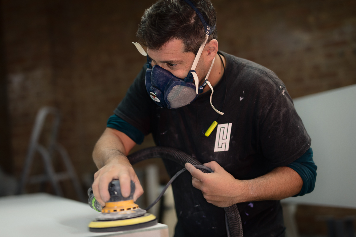 Man sanding wood wearing dust mask in workshop