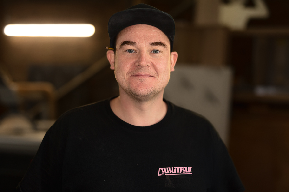 Smiling person in black shirt and cap indoors.
